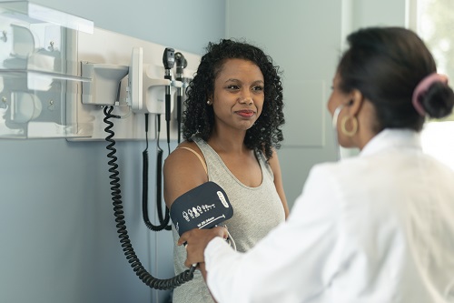 Alt text: Woman at doctor’s appointment getting her blood pressure taken