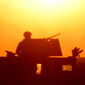 Silhouette of a soldier on a truck in front of the bright   sun