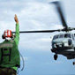 Man directing a helicopter landing on an aircraft carrier