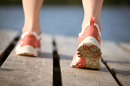Feet in athletic shoes walking on a boardwalk