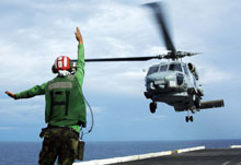 Man directing a helicopter landing on   an aircraft carrier